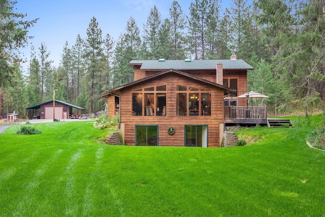 5999 E Roger Dr, Post Falls, ID 83854 - rear view of property featuring a detached garage, a lawn, a chimney, a wooden deck, and an outdoor structure