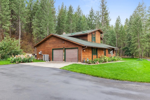 5999 E Roger Dr, Post Falls, ID 83854 - log cabin with central AC unit, a front lawn, an attached garage, asphalt driveway, and a view of trees