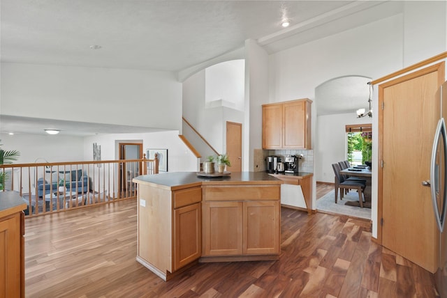 13013 E 37th Ct, Spokane Valley, WA 99206 - kitchen with arched walkways, wood finished floors, high vaulted ceiling, a chandelier, and tasteful backsplash
