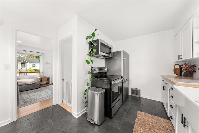 524 E Garland Ave, Spokane, WA 99207 - kitchen with stainless steel appliances, white cabinets, light countertops, and baseboards