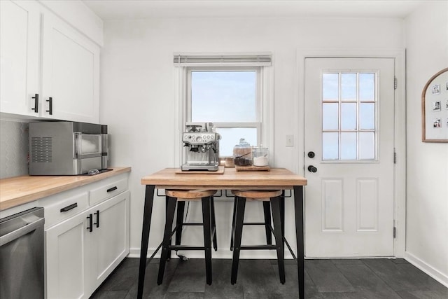 524 E Garland Ave, Spokane, WA 99207 - kitchen with stainless steel dishwasher, white cabinetry, backsplash, and baseboards