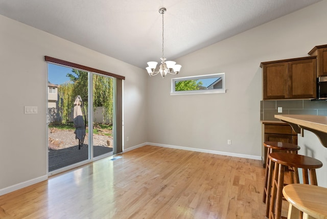 1790 N Winchester St, Liberty Lake, WA 99019 - unfurnished dining area featuring lofted ceiling, a chandelier, light wood-type flooring, healthy amount of natural light, and baseboards