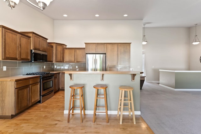 1790 N Winchester St, Liberty Lake, WA 99019 - kitchen featuring stainless steel appliances, a kitchen bar, tasteful backsplash, a towering ceiling, and light countertops