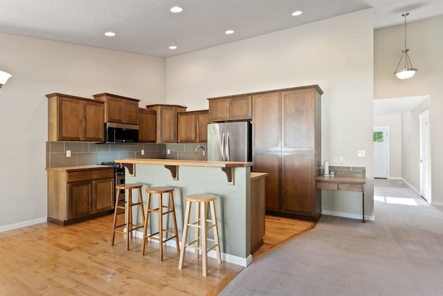 1790 N Winchester St, Liberty Lake, WA 99019 - kitchen with stainless steel appliances, a towering ceiling, a kitchen bar, baseboards, and tasteful backsplash