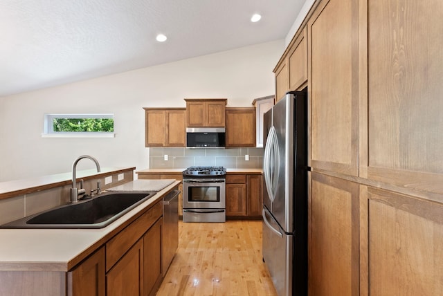 1790 N Winchester St, Liberty Lake, WA 99019 - kitchen with appliances with stainless steel finishes, a sink, vaulted ceiling, light wood-style flooring, and decorative backsplash
