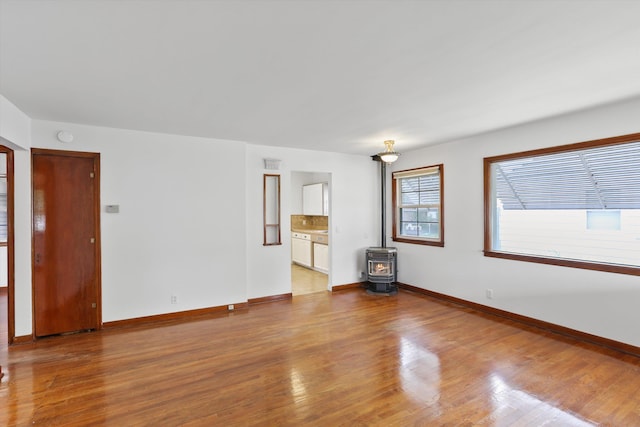 5824 N Washington St, Spokane, WA 99205 - unfurnished living room featuring a wood stove, wood finished floors, and baseboards