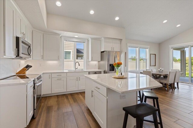 19661 E Riverwalk Ave, Liberty Lake, WA 99016 - kitchen featuring appliances with stainless steel finishes, dark wood-style floors, a kitchen breakfast bar, tasteful backsplash, and a sink
