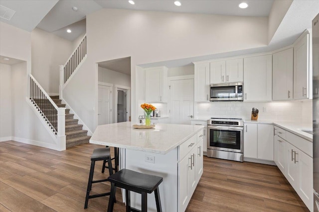 19661 E Riverwalk Ave, Liberty Lake, WA 99016 - kitchen with appliances with stainless steel finishes, a high ceiling, a breakfast bar area, a center island, and decorative backsplash