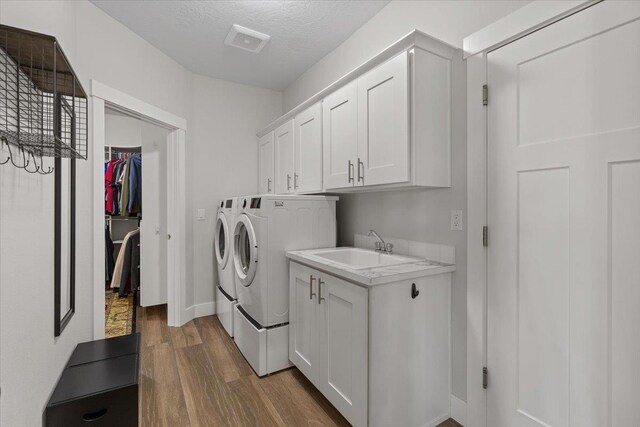 19661 E Riverwalk Ave, Liberty Lake, WA 99016 - laundry area with washing machine and dryer, dark wood-style flooring, cabinet space, and baseboards