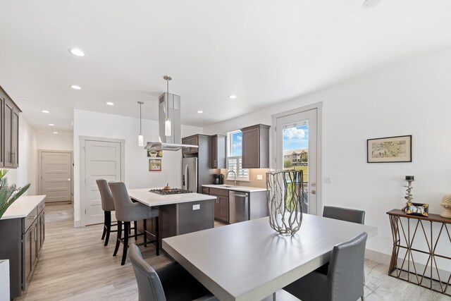 2418 N Atlas Rd, Coeur D Alene, ID 83814 - kitchen featuring island exhaust hood, appliances with stainless steel finishes, a sink, dark brown cabinets, and light countertops