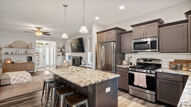 4011 S University Ct, Spokane Valley, WA 99206 - kitchen with appliances with stainless steel finishes, open floor plan, decorative backsplash, light stone countertops, and light wood-style flooring