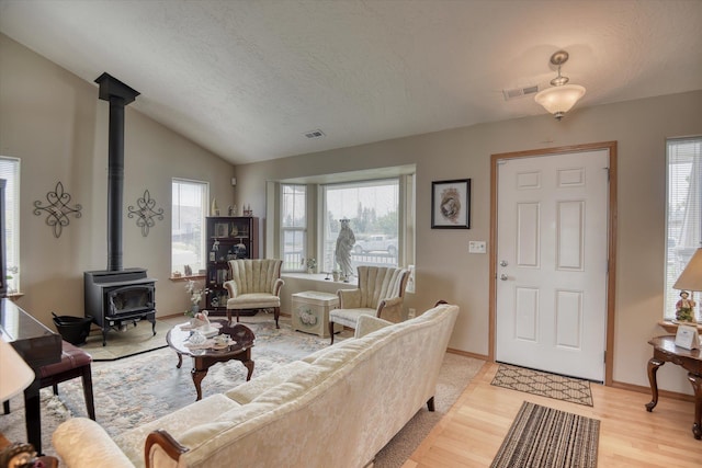 822 N Kelsea St, Medical Lake, WA 99022 - living area with a wood stove, light wood-type flooring, lofted ceiling, a textured ceiling, and baseboards