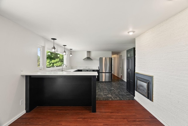 4626 E Orchard Rd, Spokane, WA 99217 - kitchen featuring freestanding refrigerator, wall chimney exhaust hood, a peninsula, light countertops, and dark wood-style flooring