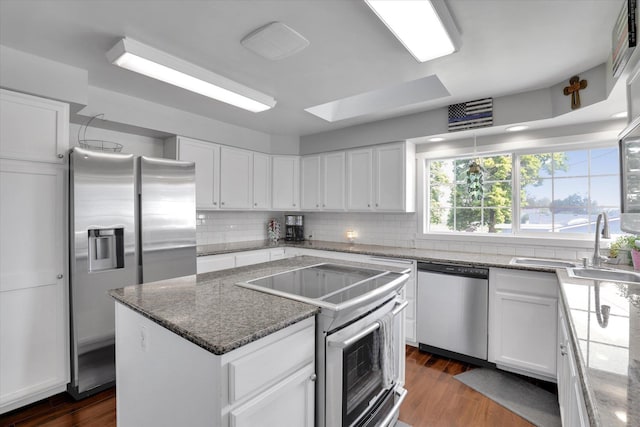 4606 S Grove Rd, Spokane, WA 99224 - kitchen featuring appliances with stainless steel finishes, a center island, decorative backsplash, white cabinetry, and dark wood-type flooring
