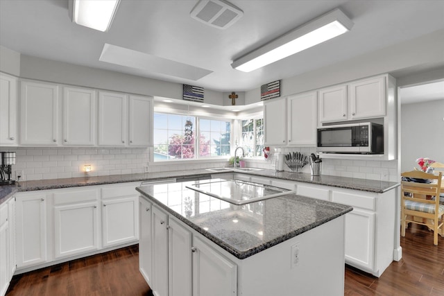 4606 S Grove Rd, Spokane, WA 99224 - kitchen with stainless steel microwave, a sink, stovetop, a center island, and backsplash