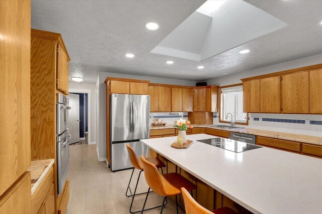 10102 N Comanche Dr, Spokane, WA 99208 - kitchen with appliances with stainless steel finishes, a sink, recessed lighting, a breakfast bar, and light countertops