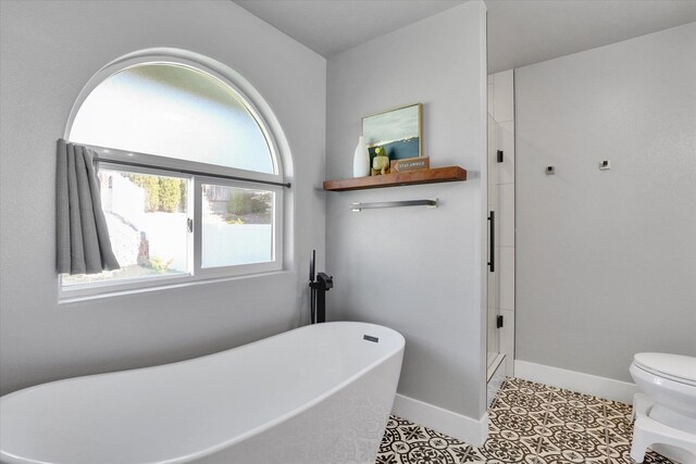 10102 N Comanche Dr, Spokane, WA 99208 - full bathroom featuring a soaking tub, a stall shower, baseboards, toilet, and tile patterned floors