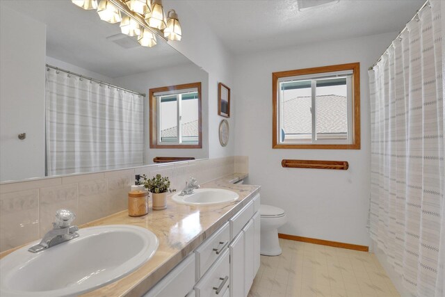 10102 N Comanche Dr, Spokane, WA 99208 - full bathroom featuring double vanity, toilet, backsplash, a chandelier, and baseboards