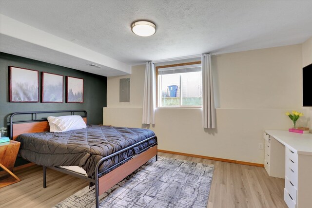 10102 N Comanche Dr, Spokane, WA 99208 - bedroom featuring electric panel, light wood finished floors, baseboards, and a textured ceiling