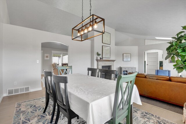 10102 N Comanche Dr, Spokane, WA 99208 - dining room featuring lofted ceiling, arched walkways, wood finished floors, and a fireplace
