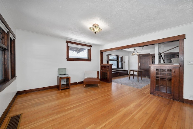 617 W Carlisle Ave, Spokane, WA 99205 - living room with light wood-style flooring, baseboards, a textured ceiling, and a chandelier