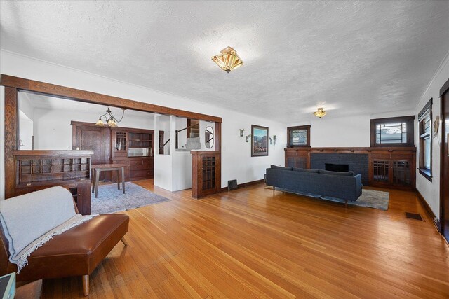617 W Carlisle Ave, Spokane, WA 99205 - living room with a textured ceiling, light wood-style flooring, a fireplace, and baseboards