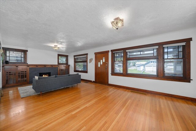 617 W Carlisle Ave, Spokane, WA 99205 - living area featuring a textured ceiling, baseboards, light wood finished floors, and a brick fireplace