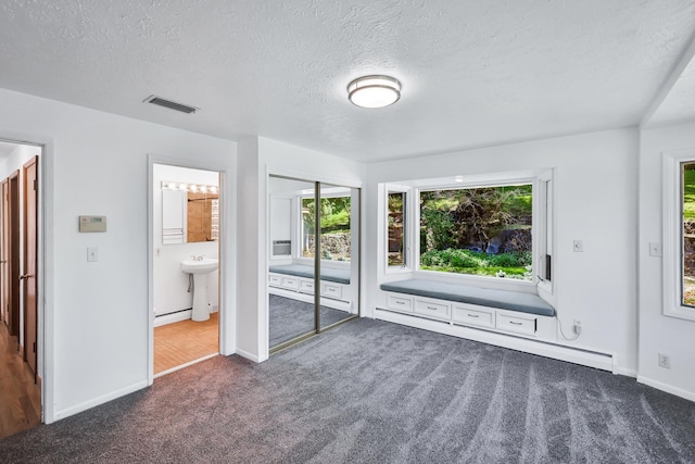 10401 N College Cir, Spokane, WA 99218 - unfurnished bedroom with carpet flooring, multiple windows, a textured ceiling, baseboards, and a baseboard heating unit