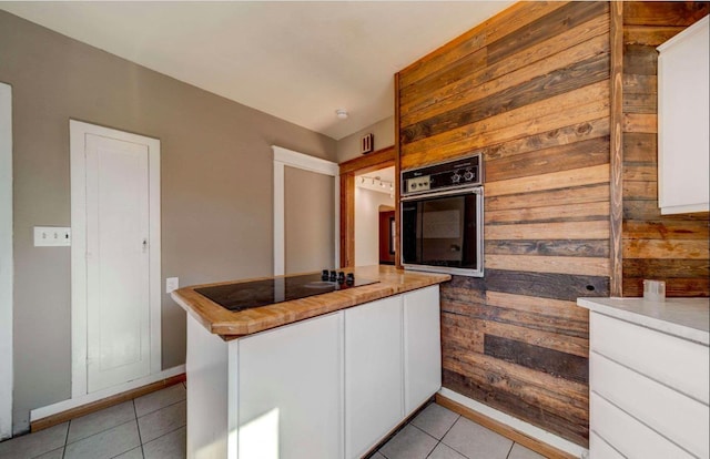 18 N 7th St, Cheney, WA 99004 - kitchen featuring black appliances, wooden walls, white cabinetry, light tile patterned flooring, and baseboards