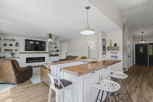 12621 N E Newman Lake Dr, Newman Lake, WA 99025 - kitchen with butcher block counters, a ceiling fan, a breakfast bar area, light wood-style floors, and a textured ceiling