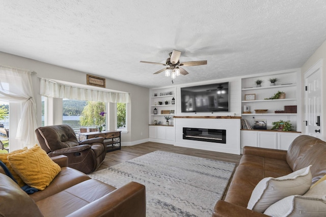 12621 N E Newman Lake Dr, Newman Lake, WA 99025 - living room with a textured ceiling, a ceiling fan, wood finished floors, a glass covered fireplace, and baseboards