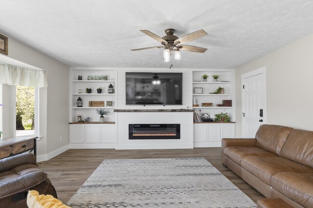 12621 N E Newman Lake Dr, Newman Lake, WA 99025 - living room featuring ceiling fan, wood finished floors, a glass covered fireplace, a textured ceiling, and built in shelves