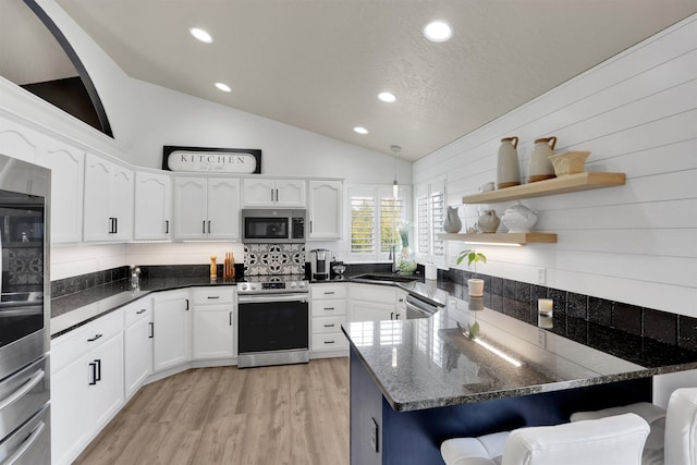 8310 E Bull Pine Ln, Spokane, WA 99217 - kitchen with appliances with stainless steel finishes, a peninsula, vaulted ceiling, white cabinetry, and a breakfast bar