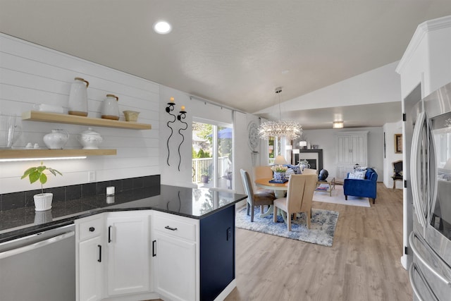 8310 E Bull Pine Ln, Spokane, WA 99217 - kitchen with stainless steel appliances, lofted ceiling, open floor plan, dark countertops, and light wood-style flooring