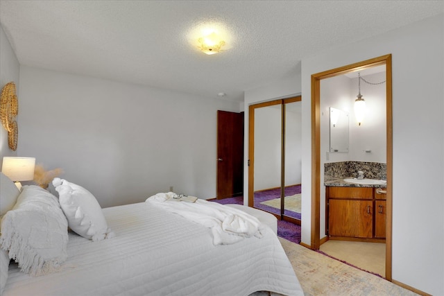 2651 E 35th Ave, Spokane, WA 99223 - bedroom featuring a sink, a closet, ensuite bath, light carpet, and a textured ceiling