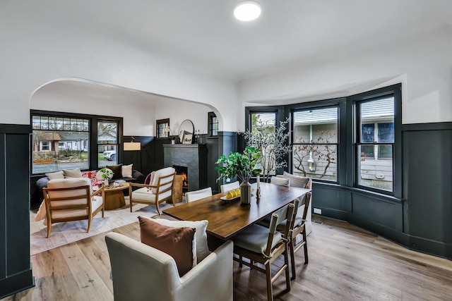 613 W Kiernan Ave, Spokane, WA 99205 - dining space featuring a high end fireplace, arched walkways, light wood-style flooring, wainscoting, and a decorative wall