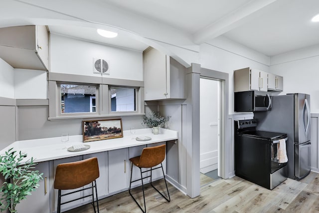 613 W Kiernan Ave, Spokane, WA 99205 - kitchen with stainless steel appliances, light wood-style flooring, a breakfast bar area, light countertops, and beamed ceiling