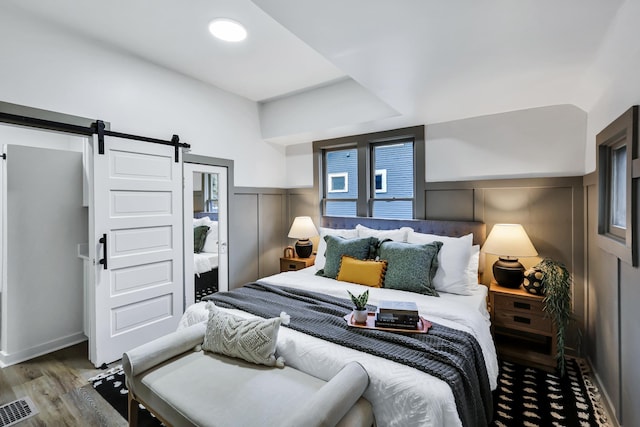 613 W Kiernan Ave, Spokane, WA 99205 - bedroom with a barn door, wood finished floors, wainscoting, and a decorative wall