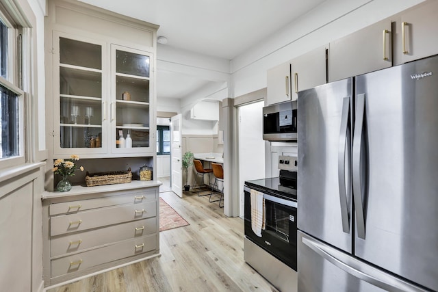 613 W Kiernan Ave, Spokane, WA 99205 - kitchen featuring appliances with stainless steel finishes, light wood-style flooring, light countertops, and glass insert cabinets