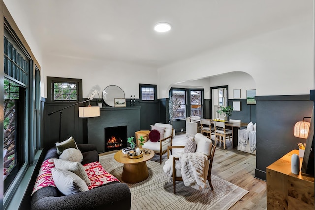 613 W Kiernan Ave, Spokane, WA 99205 - living room featuring a warm lit fireplace, wood finished floors, arched walkways, and healthy amount of natural light