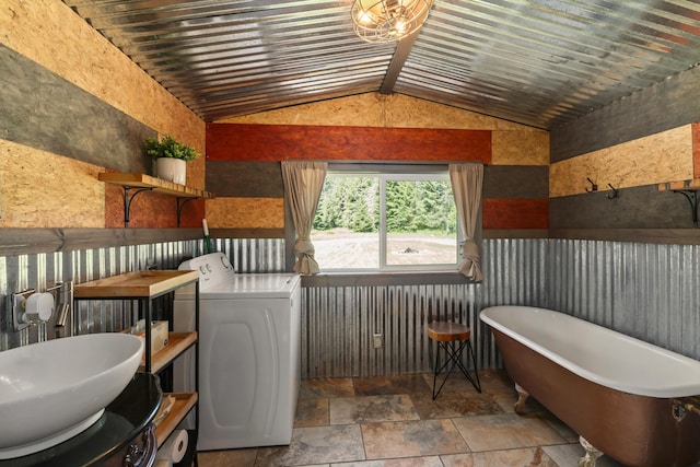 1100 Graham Rd, Cusick, WA 99119 - bathroom with washer / clothes dryer, a soaking tub, stone finish flooring, lofted ceiling, and a sink