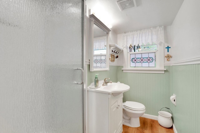 1211 W 17th Ave, Spokane, WA 99203 - bathroom featuring vanity, a shower stall, wood finished floors, toilet, and a wainscoted wall