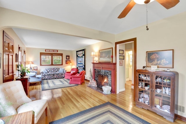 1211 W 17th Ave, Spokane, WA 99203 - living area featuring arched walkways, wood finished floors, a fireplace, and ceiling fan