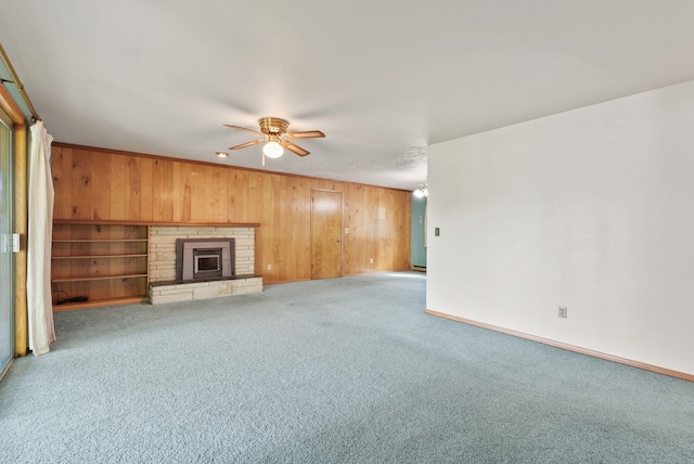 11132 S Silver Lake Rd, Medical Lake, WA 99022 - unfurnished living room featuring wood walls, a ceiling fan, carpet floors, baseboards, and a glass covered fireplace
