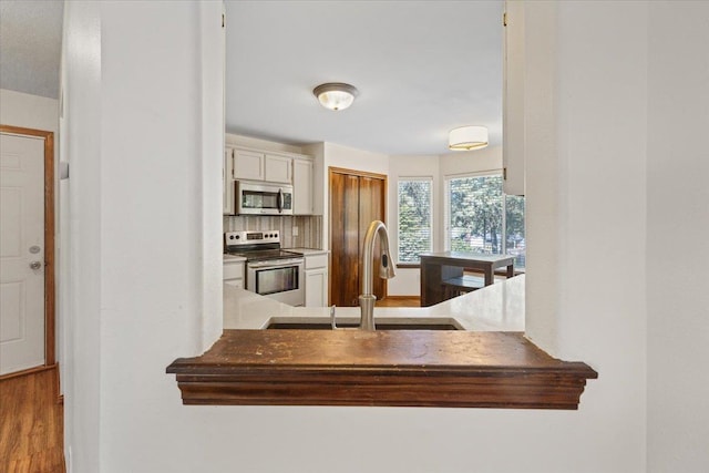 4227 E 38th Ave, Spokane, WA 99223 - kitchen with stainless steel appliances, a sink, decorative backsplash, and white cabinets