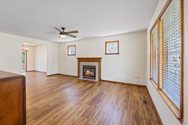 4227 E 38th Ave, Spokane, WA 99223 - unfurnished living room featuring wood finished floors, a chandelier, a tiled fireplace, and baseboards