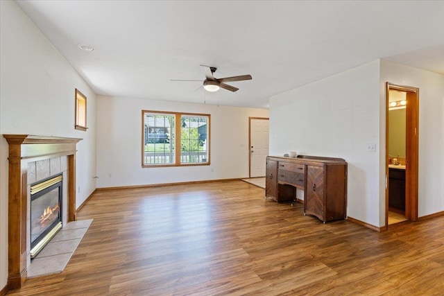 4227 E 38th Ave, Spokane, WA 99223 - unfurnished living room with a ceiling fan, light wood-style flooring, a tiled fireplace, and baseboards