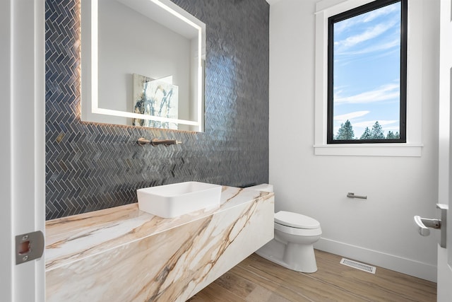 13858 N Boulder Park Ln, Spokane, WA 99208 - bathroom with baseboards, toilet, wood finished floors, backsplash, and vanity