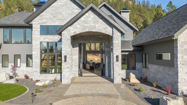 13858 N Boulder Park Ln, Spokane, WA 99208 - doorway to property with stone siding, a chimney, and roof with shingles