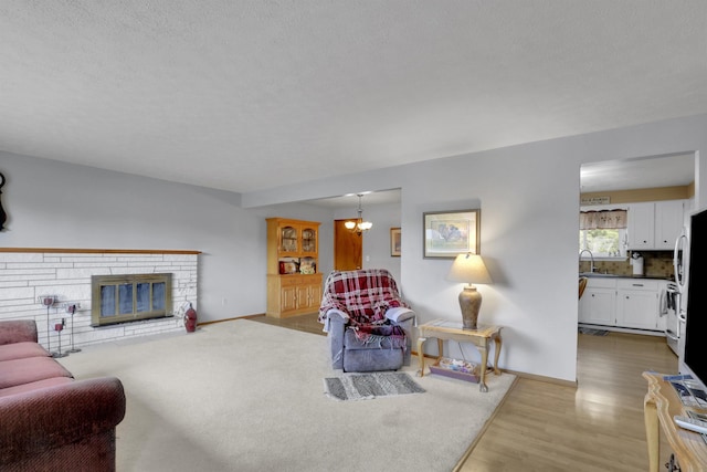 11307 E 8th Ave, Spokane Valley, WA 99206 - living room featuring wood finished floors, baseboards, a textured ceiling, and a stone fireplace